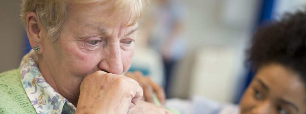 Senior woman with dementia in hospital while nurse helps