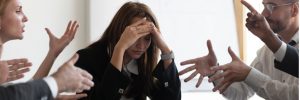 Stressed woman surrounded by arguing colleagues.