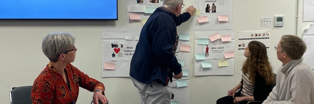 People discussing notes on wall.