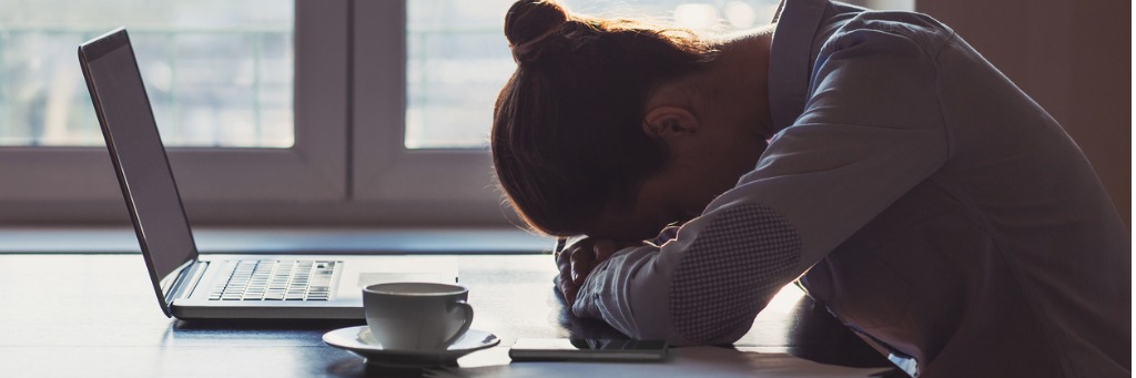 Person resting head on desk.